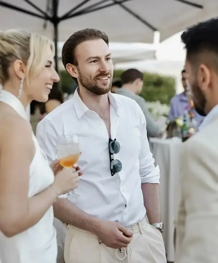 Ein Mann im weißen Hemd, der auf einer Hochzeit mit Leuten spricht