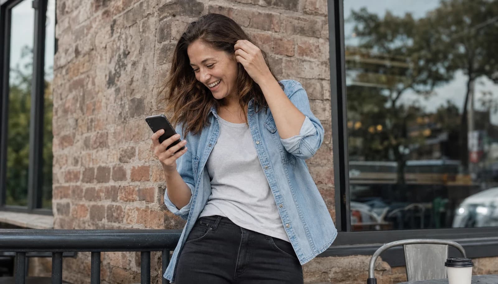 Una donna che ride di gusto guardando il suo telefono, probabilmente per una frase divertente ricevuta su un'app di dating.