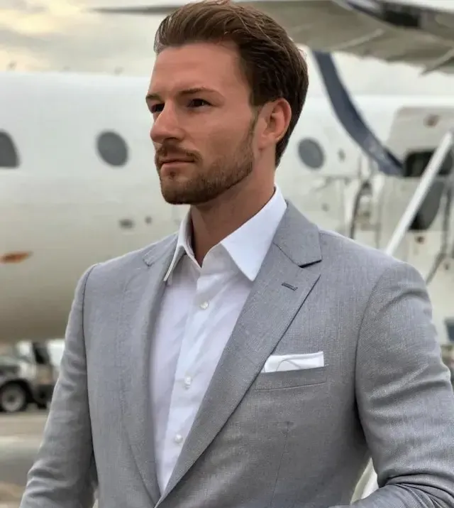 Een man in een pak staat voor een privéjet