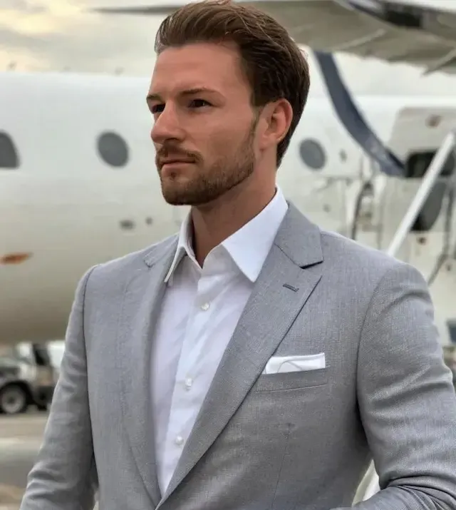 A man in a suit standing in front of a private jet