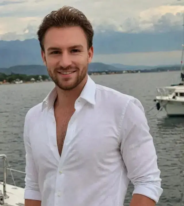 A man wearing a white shirt on a boat looking confidently at the camera