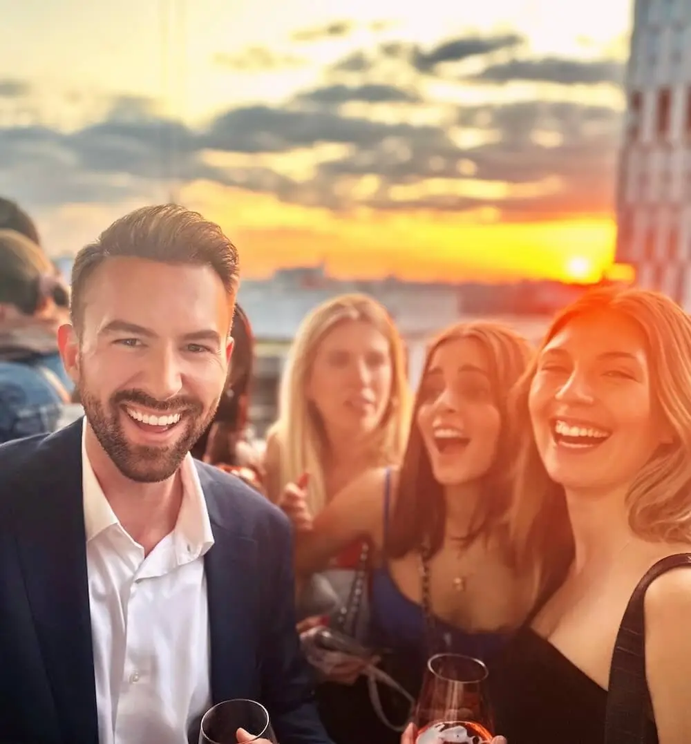 A man at a rooftop party laughing with woman